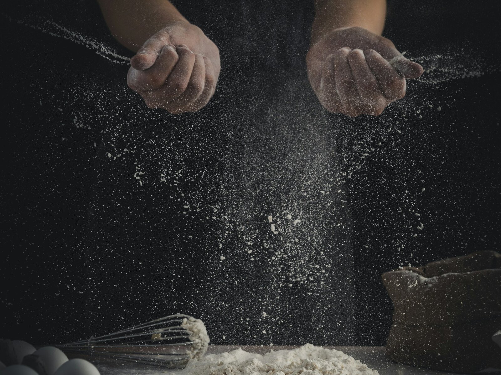 Hands kneading dough on a floured bench
